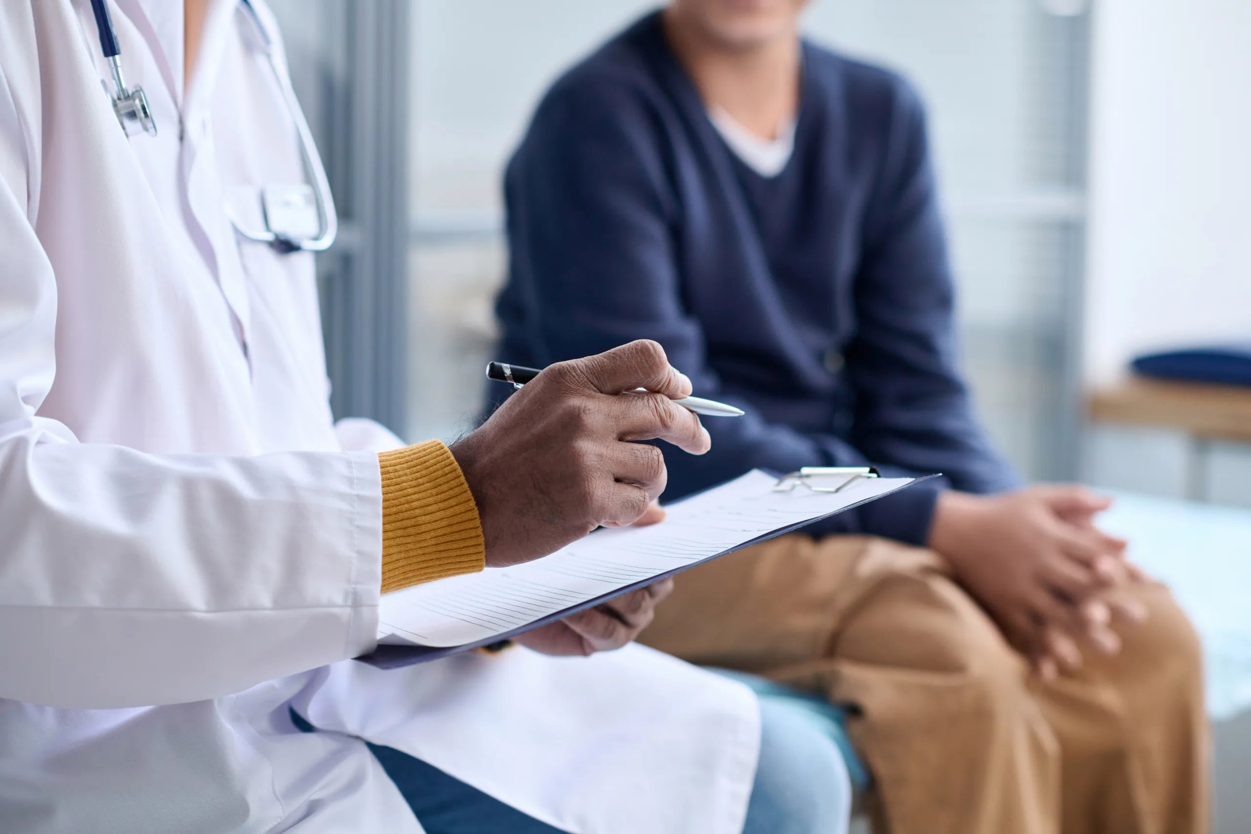 Side view closeup of Middle Eastern doctor holding clipboard while consulting child in clinic copy space