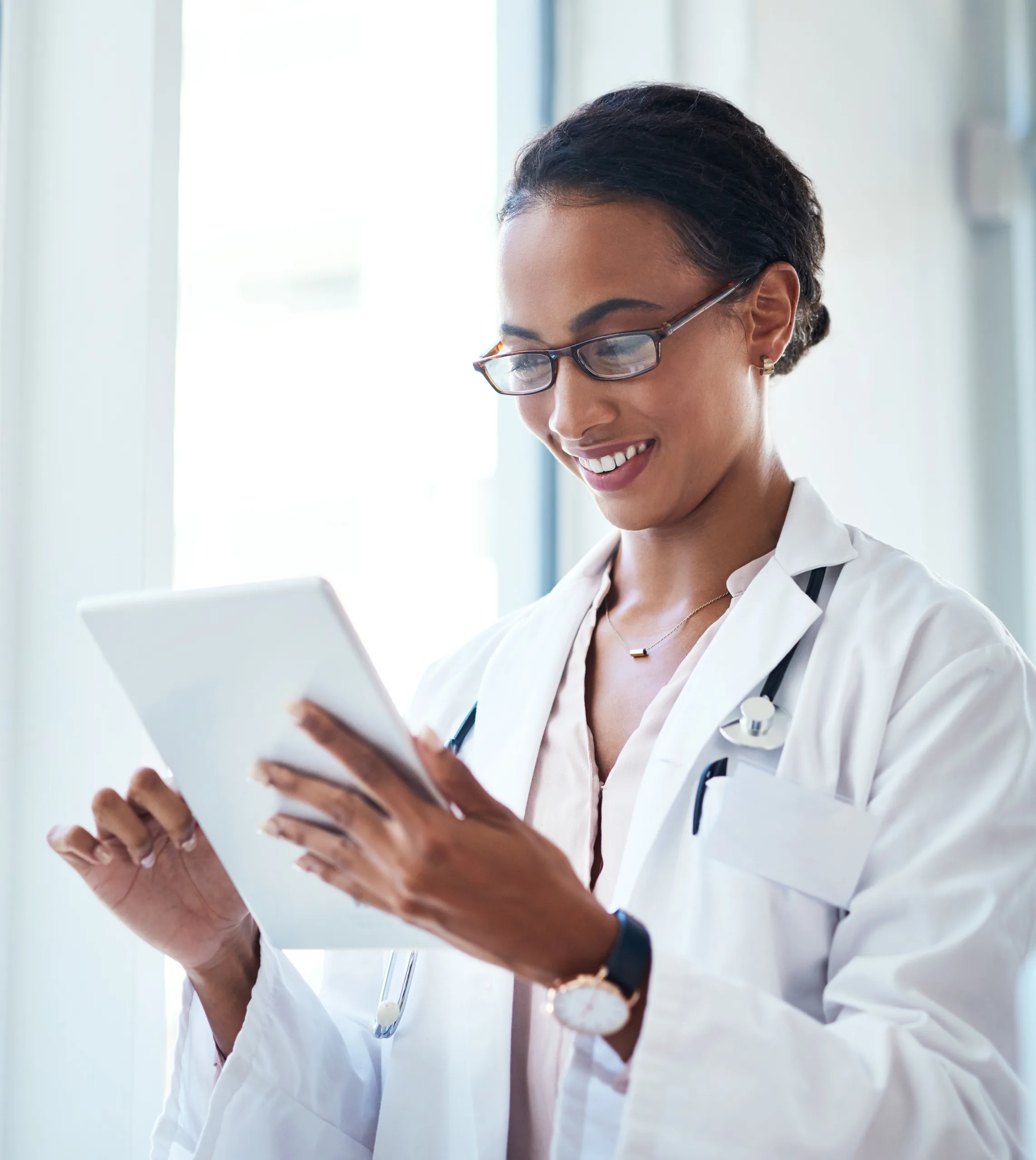 A confident healthcare professional in a white coat smiles while reviewing information on a tablet in a bright medical office, reflecting innovation and patient care at Alimentiv.